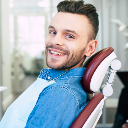 Smiling man in dental chair wearing a bib, representing a positive dental visit experience.