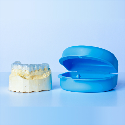 Dental night guard on a mold next to a blue protective storage case.