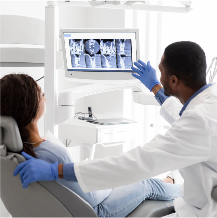 Dentist showing a patient dental X-rays on a monitor during an oral health exam.