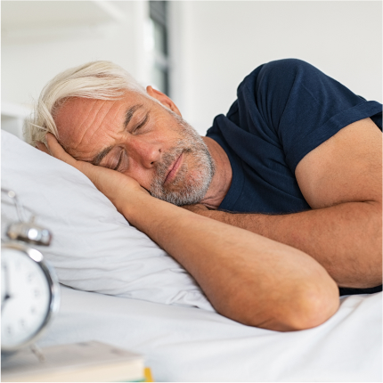Older man peacefully sleeping in bed, representing relief from sleep apnea with treatment.