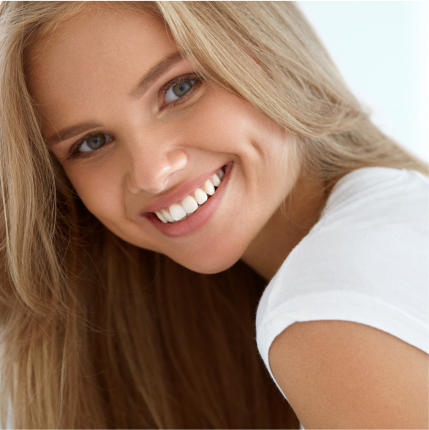 Smiling woman with straight white teeth and blonde hair, representing dental care results.