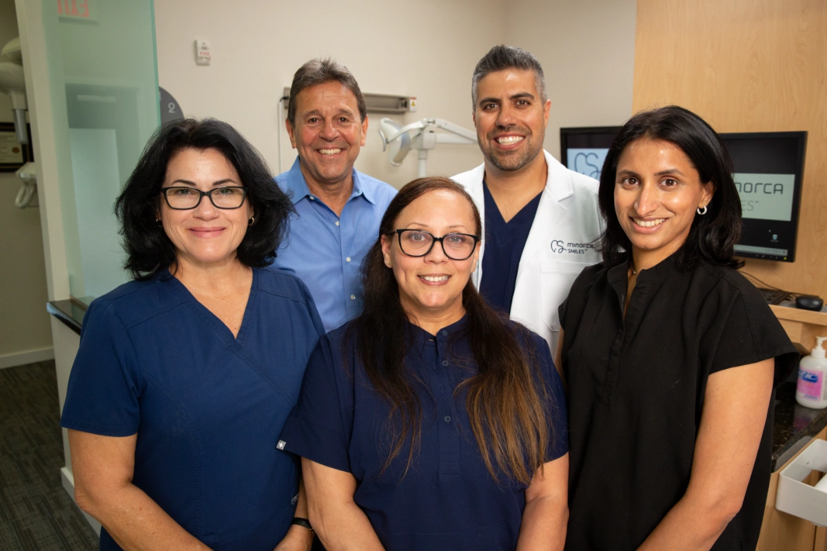 Minorca Smiles dental team smiling inside clinic with Dr. del Castillo in white coat.
