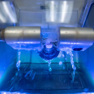 Close-up of CEREC machine crafting a dental crown with precision and water spray.