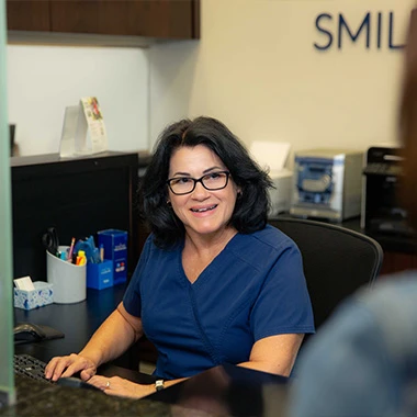 Smiling receptionist welcoming a patient at Minorca Smiles front desk.