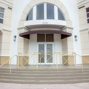 Exterior entrance to Minorca Smiles building with stairway and railing.